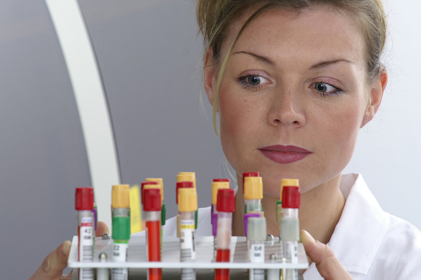 Labormedizinerin trägt Set mit Blutoproben ins Labor