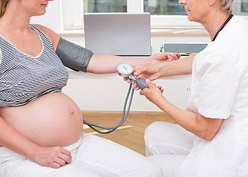 Ärztin misst den Blutdruck einer Schwangeren.