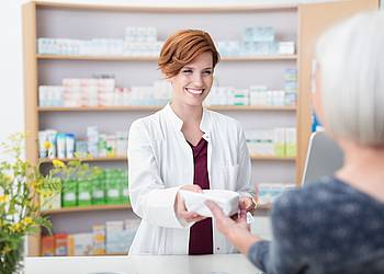 Apothekerin übergibt Patientin ein rezeptfreies Medikament.