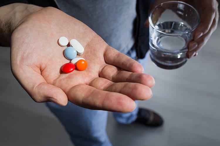 Frau hält viele Tabletten in der Hand.