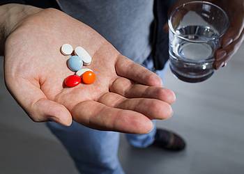 Frau hält viele Tabletten in der Hand.