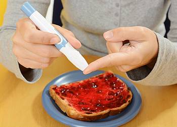 Person misst eigenen Blutzuckerspiegel mit Blutzuckermessgerät am Finger