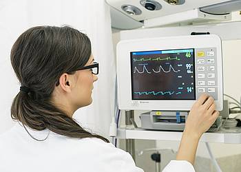 Frau betrachtet EKG auf Monitor.