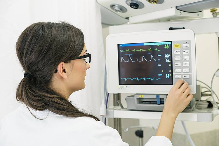 Frau betrachtet EKG auf Monitor.