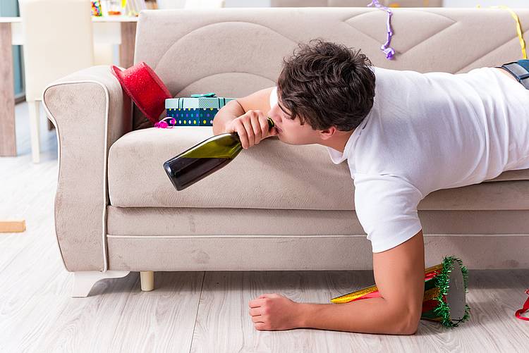 Junger Mann liegt nach Kanrevalsparty betrunken auf dem Sofa