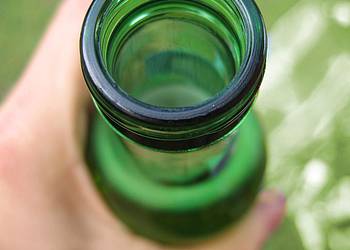 Hand hält offene Bierflasche
