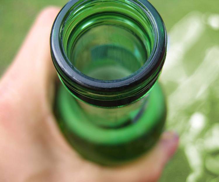 Hand hält offene Bierflasche