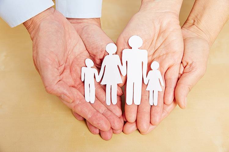 Familien-Scherenschnitt liegt auf Handflächen von Mann und Frau