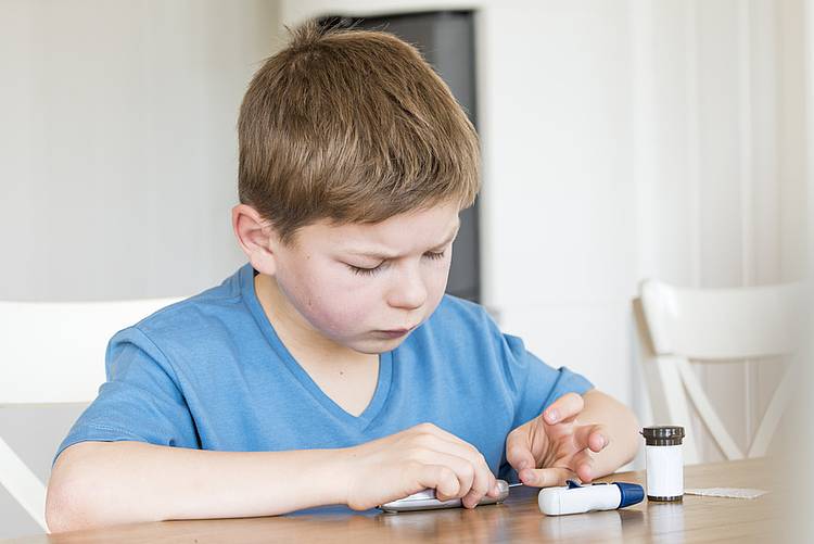 Kleiner Junge misst seinen Blutzuckerwert