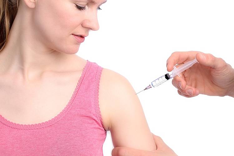 Frau erhält Impfung in den Oberarm. 