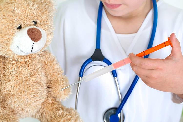 Eine Ärztin gibt einem Teddybär eine Imfung.