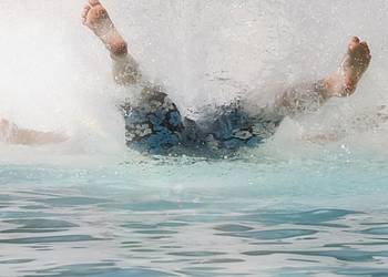 Junger Mann macht Arschbombe im Freibad