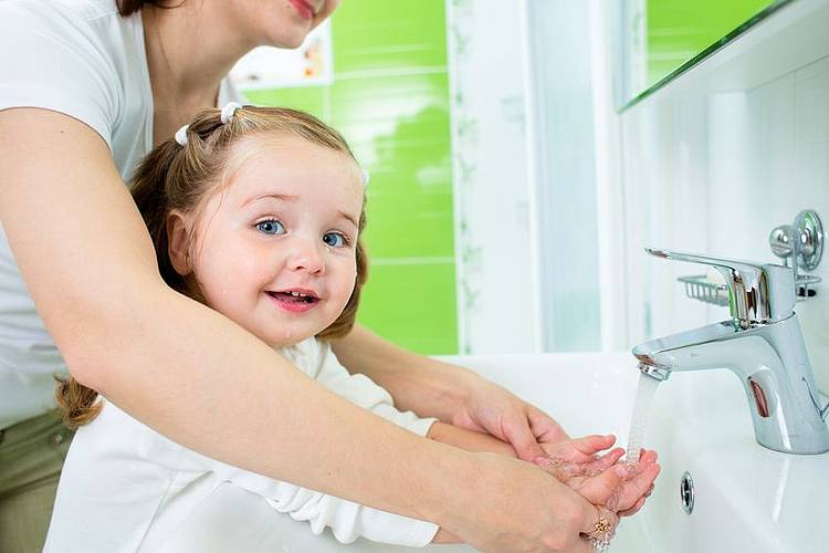 Ein kleines Mädchen wäscht sich mit Mutter gemeinsam im Bad die Hände.  