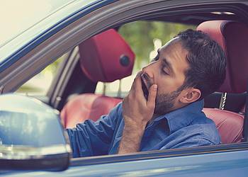 Junger Mann gähnt im Auto