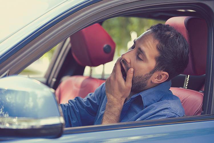Junger Mann gähnt im Auto