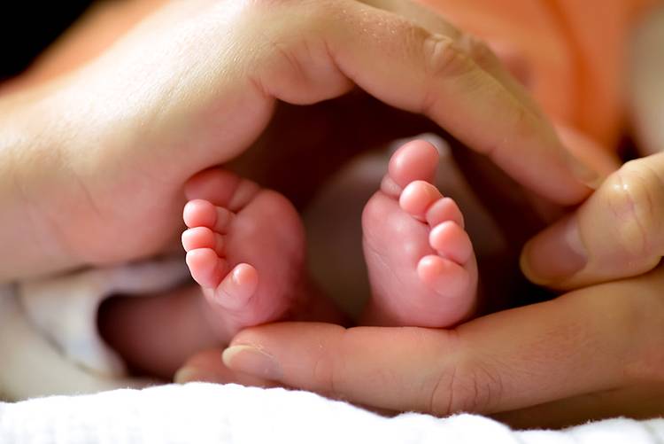 Füße von Neugeborenem in Händen gehalten