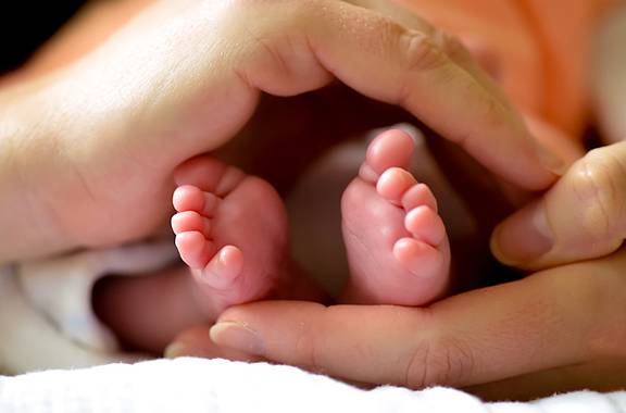 Füße von Neugeborenem in Händen gehalten