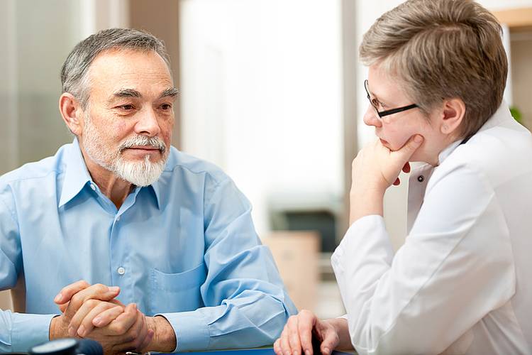 Älterer Mann lässt sich von Ärztin zu Behandlung bei Prostatakrebs beraten.