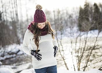 Schwangere Frau im verschneiten Winterwald