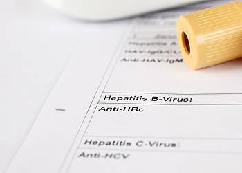 Laborröhrchen liegt auf Testbericht zu Hepatitis A, Hepatitis B und Hepatitis C.