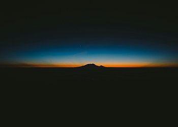 Das Foto zeigt einen Sonnenaufgang: Am Horizont leuchtet ein roter Streifen Himmel.