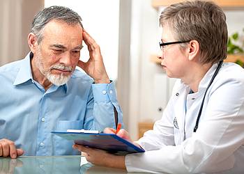Ärztin berät einen älteren Mann zu personalisierter Medizin bei Darmkrebs
