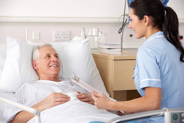 Patient im Krankenhausbett bespricht Blutwerte mit Ärztin.