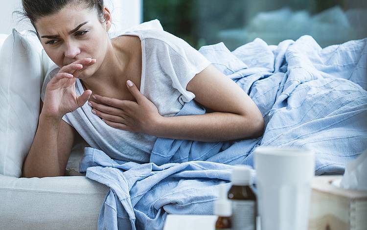 Frau mit Husten oder Tuberkulose liegt krank im Bett.