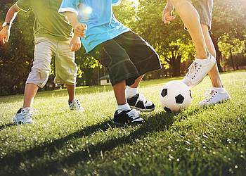 Familie spielt Fußball auf sonniger Wiese