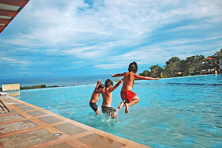 Kinder springen ins Wasser im Freibad