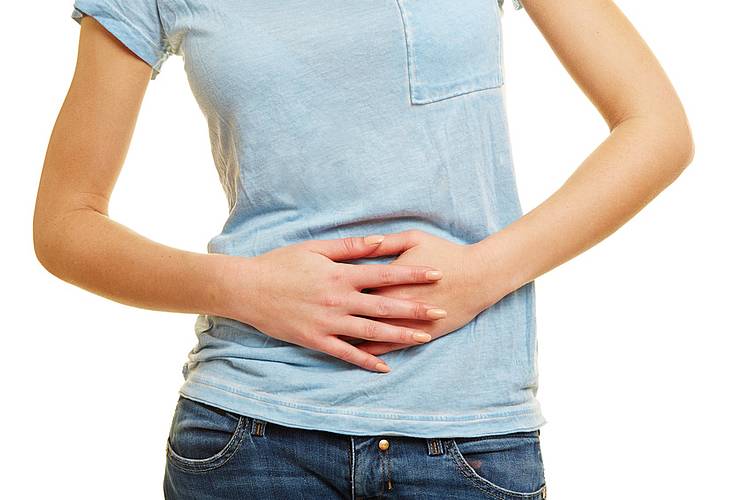 Junge Frau hält sich den schmerzenden Bauch