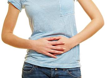 Junge Frau hält sich den schmerzenden Bauch