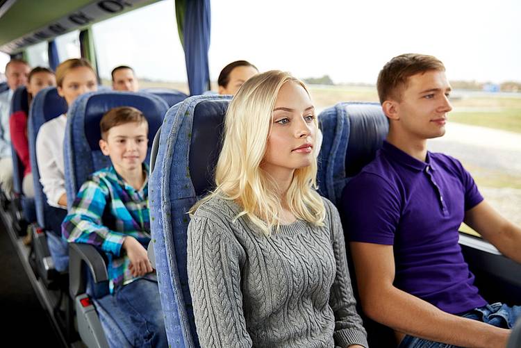 Touristen sitzen eng zusammengedrängt im Reisebus.