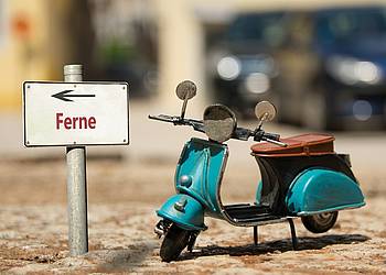Modell einer Vespa steht vor kleinem Wegweiser mit Aufschrift "Ferne"