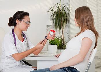 Frauenärztin berät Schwangere zu Vorsorgeuntersuchungen