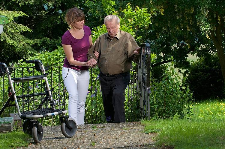 Pflegekraft mit Parkinson-Patient und Rollator