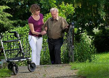 Pflegekraft mit Parkinson-Patient und Rollator