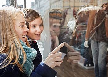 Junge Frauen zeigen mit blassen, kalten Fingern auf die Auslage in einem  Schaufenster.
