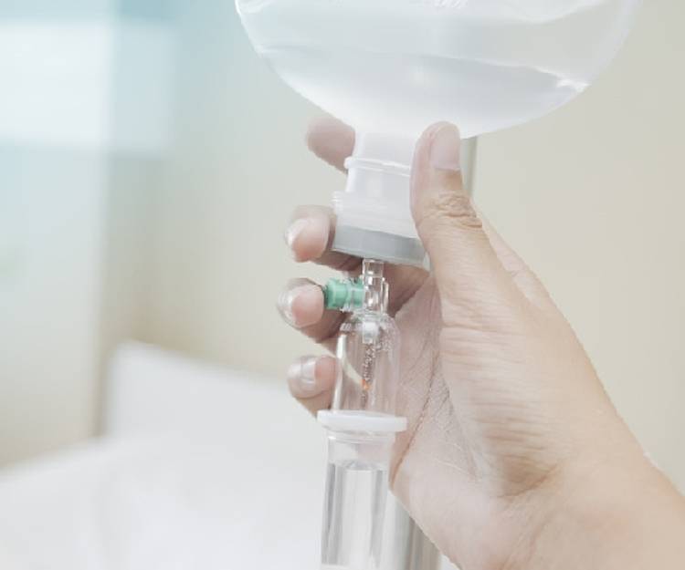 Frauenhand stellt Infusion gegen Thrombose ein.