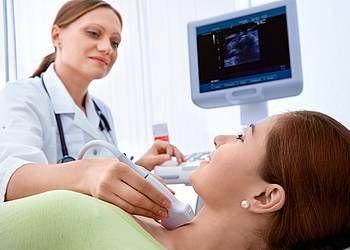 Ärztin untersucht Schilddrüse einer Patientin mit Ultraschall. 