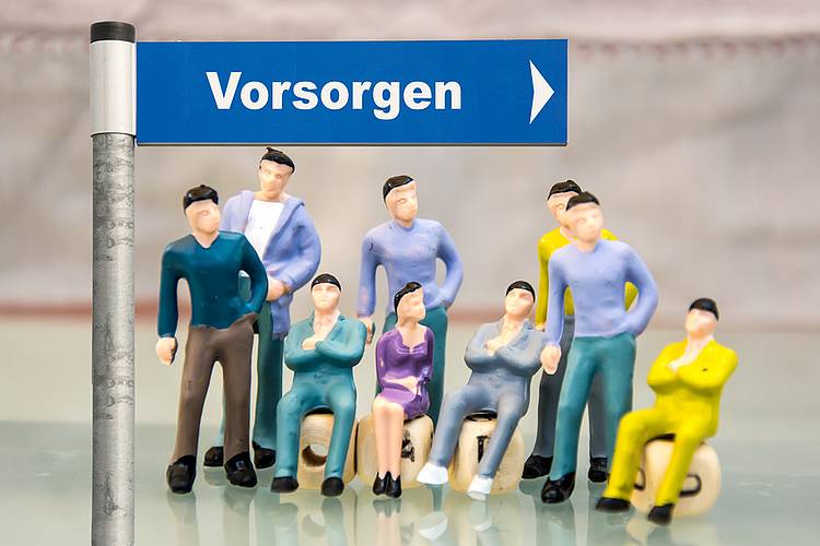 Kleine Figuren unter einem Straßenschild mit dem Schriftzug "Vorsorge"