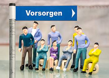 Kleine Figuren unter einem Straßenschild mit dem Schriftzug "Vorsorge"