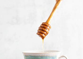 Honig tropft in eine Tasse