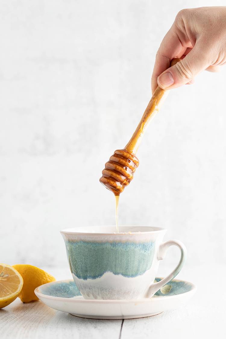 Honig tropft in eine Tasse