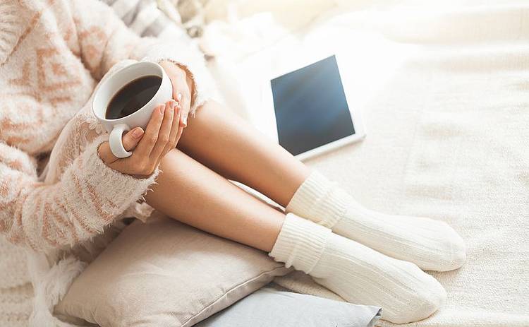 Frau mit dickem Pullover und Kaffeetasse